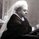 photo of Queen Victoria seated at desk, in thought, writing